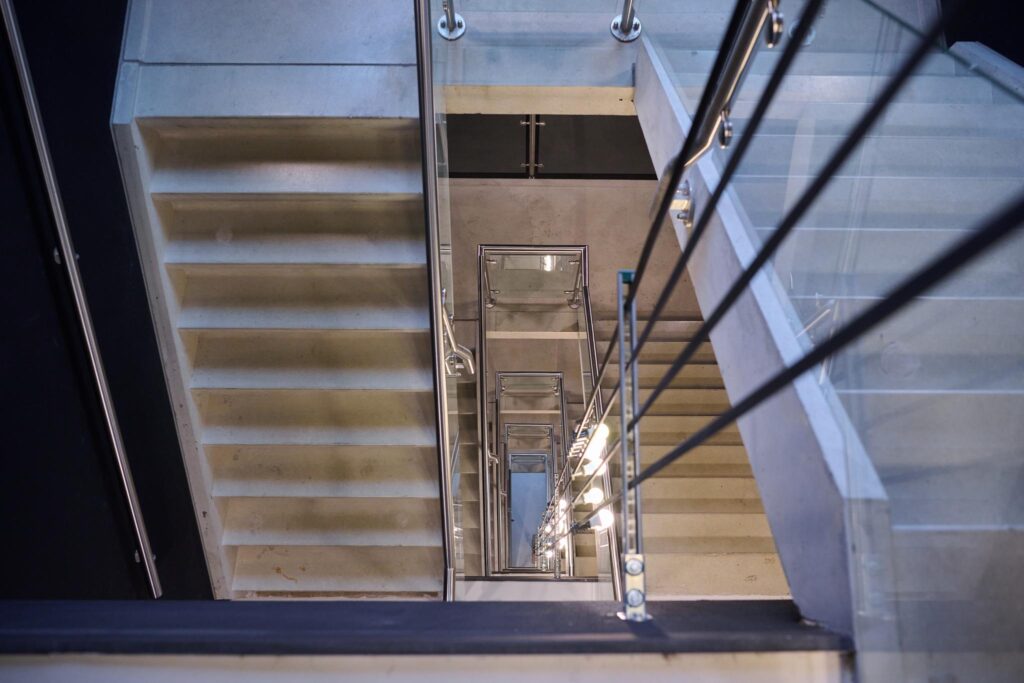 Doorkijk in een modern trappenhuis met betonnen treden en glazen balustrades in een gebouw aan het John M. Keynesplein.